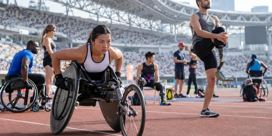 Para sportisti stadionā iesildās pirms sacensībām, tostarp sportiste sacensību riteņkrēslā