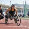 Para sportiste sacensību riteņkrēslā gatavojas startam kopā ar treneri stadionā