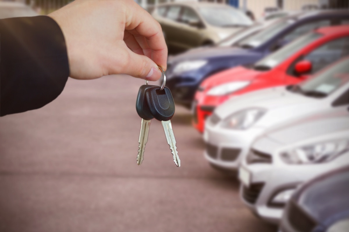 Rokās tur atslēgas fonā auto rinda