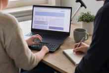Cilvēks ar ierobežotu roku kustību testē tīmekļvietni ar tastatūru, kamēr kolēģis pieraksta novērojumus.