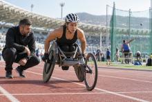 Para sportiste sacensību riteņkrēslā gatavojas startam kopā ar treneri stadionā