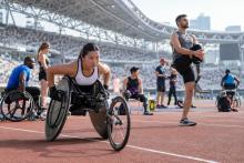 Para sportisti stadionā iesildās pirms sacensībām, tostarp sportiste sacensību riteņkrēslā