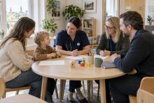 Bērns ar vecāku un trim speciālistiem pie apaļa galda kopīgi pārrunā atbalsta plānu