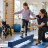 Meitene rehabilitācijas nodarbībā trenē līdzsvaru kopā ar fizioterapeiti